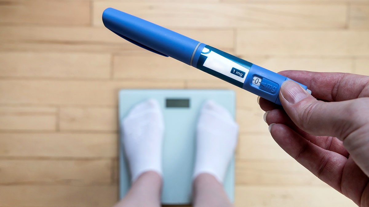 Ozempic Insulin injection pen for diabetics and weight loss. Woman weighs herself and holds Ozempic in her hand.