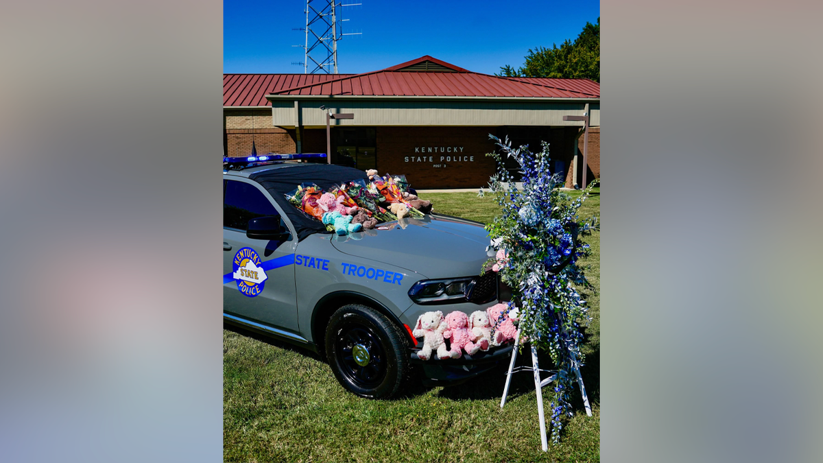 Flowers and stuffed animals cover a Kentucky State Police cruiser outside Post 3 in Bowling Green