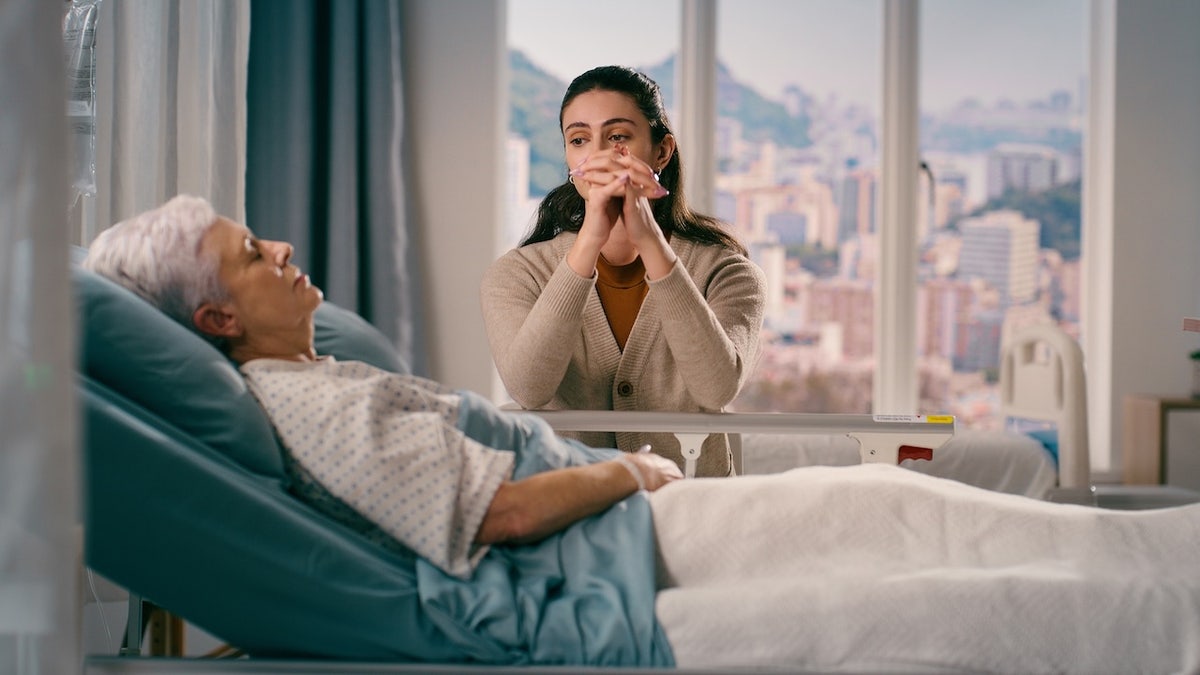 Woman praying over older adult