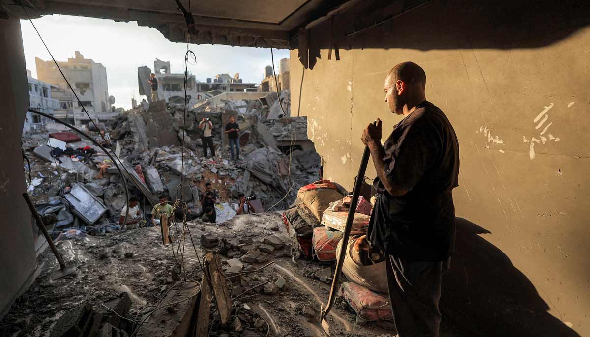 A man stands next to salvaged items as people search the rubble of a collapsed building following overnight Israeli airstrikes in Gaza City on October 9, 2026. — Reuters