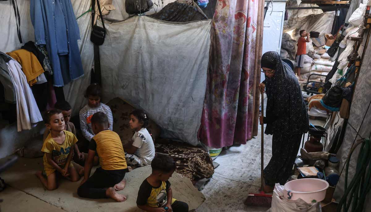A 35-year-old displaced Palestinian woman from Beit Hanoun, sweeping the floor of the makeshift shelter where she lives with her husband and their six children in Khan Yunis, in the southern Gaza Strip. — AFP