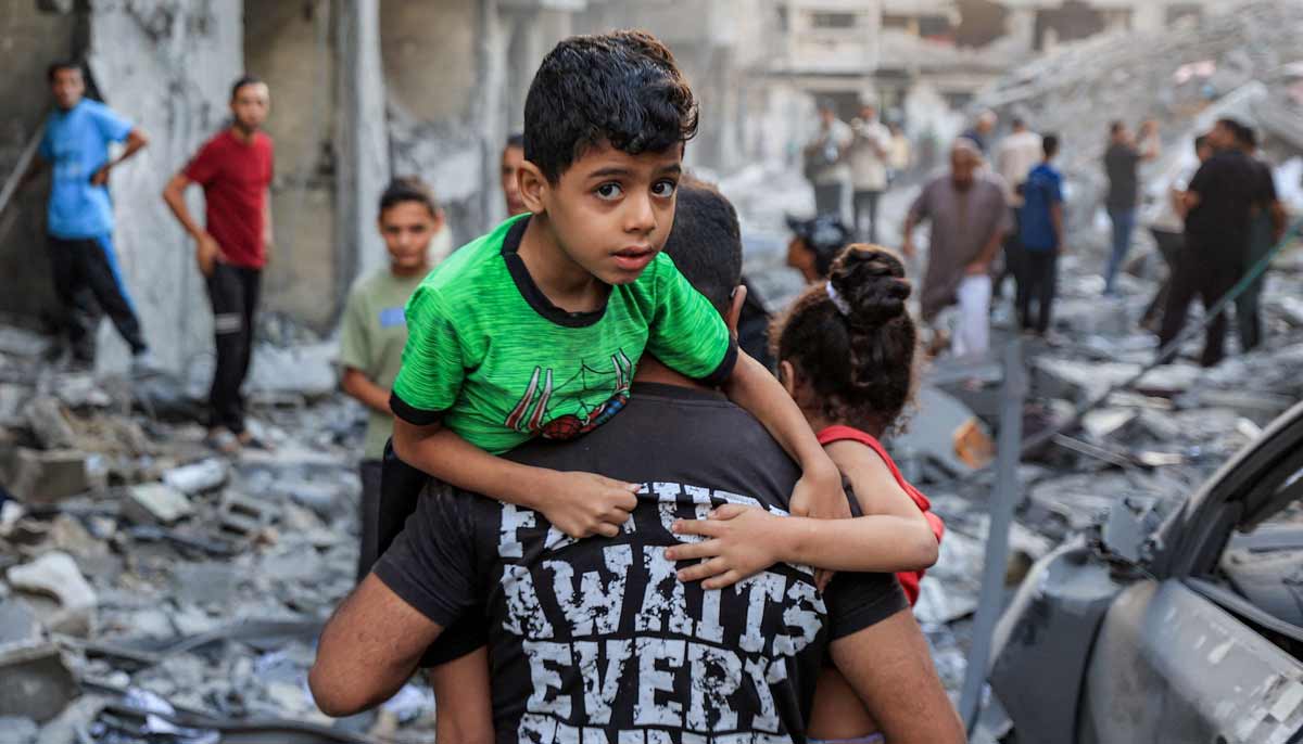 A man carries a boy near the rubble of a collapsed building as people search the site following overnight Israeli airstrikes in Gaza City on October 9, 2026. — AFP