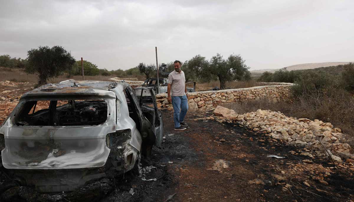 A Palestinian man looks at vehicles reportedly set alight by Israeli settlers in Palestinian-owned olive groves near the village of Turmus Ayya, north of the city of Ramallah in the Israeli-occupied West Bank on October 16, 2026. — AFP