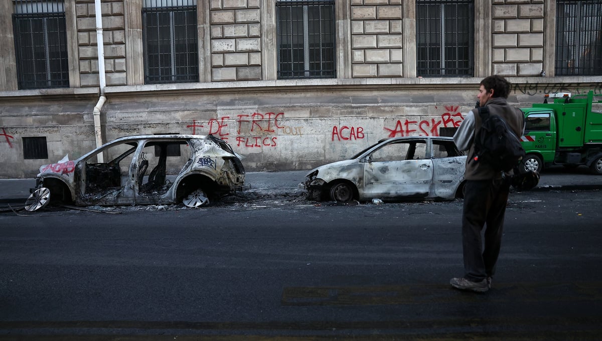 A person walks past burnt out vehicles on a street, the day after clashes during a national day of demonstrations against the cost of living and rising fuel prices, near the Place de la Republique in Paris, France, October 18, 2026. — Reuters