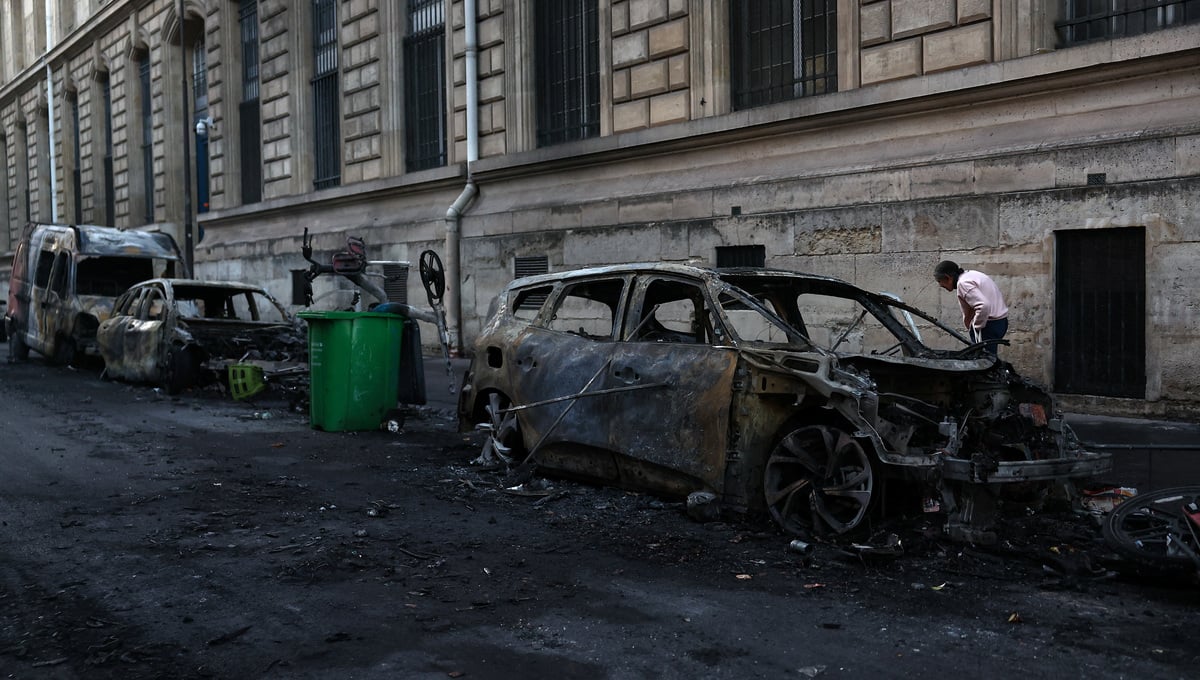 A person stands next to burnt out vehicles on a street, the day after clashes during a national day of demonstrations against the cost of living and rising fuel prices, near the Place de la Republique in Paris, France, October 18, 2026. — Reuters