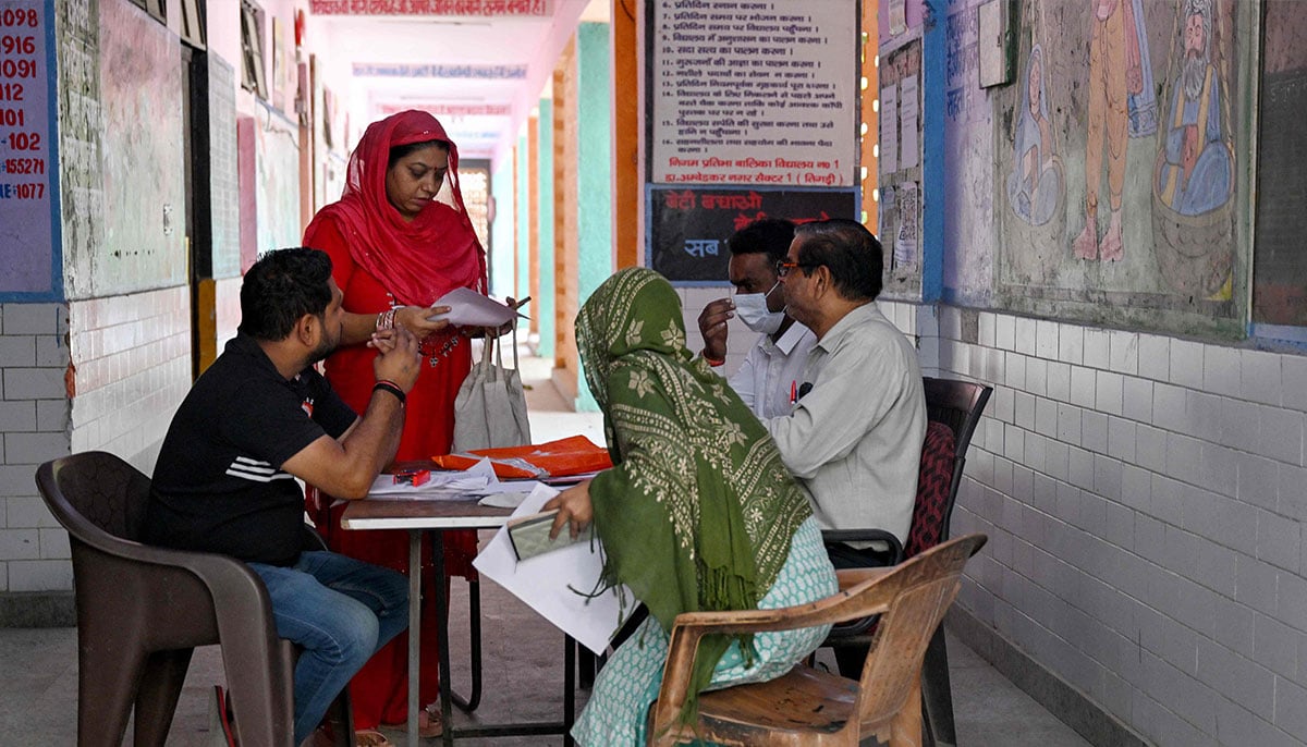 Booth level-officer (BLO) Mukesh Khanna (R) assists people to register their documents for the Draft Electoral Roll 2026 as part of the Election Commission of Indias Special Intensive Revision (SIR), at a voter verification camp in New Delhi on October 18, 2026. — AFP