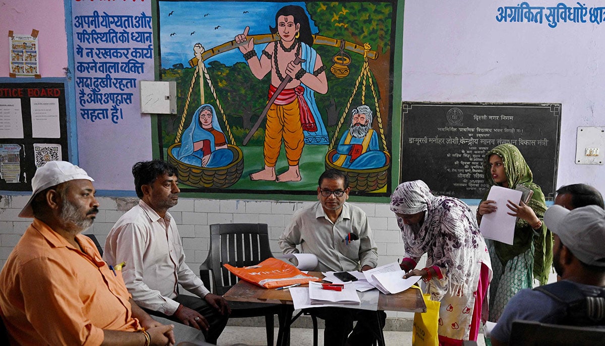Booth level-officer (BLO) Mukesh Khanna (3L) assists Laddli Khatun (3R), a slum dweller to register for the Draft Electoral Roll 2026 as part of the Election Commission of Indias Special Intensive Revision (SIR), at a voter verification camp in New Delhi on October 18, 2026. — AFP