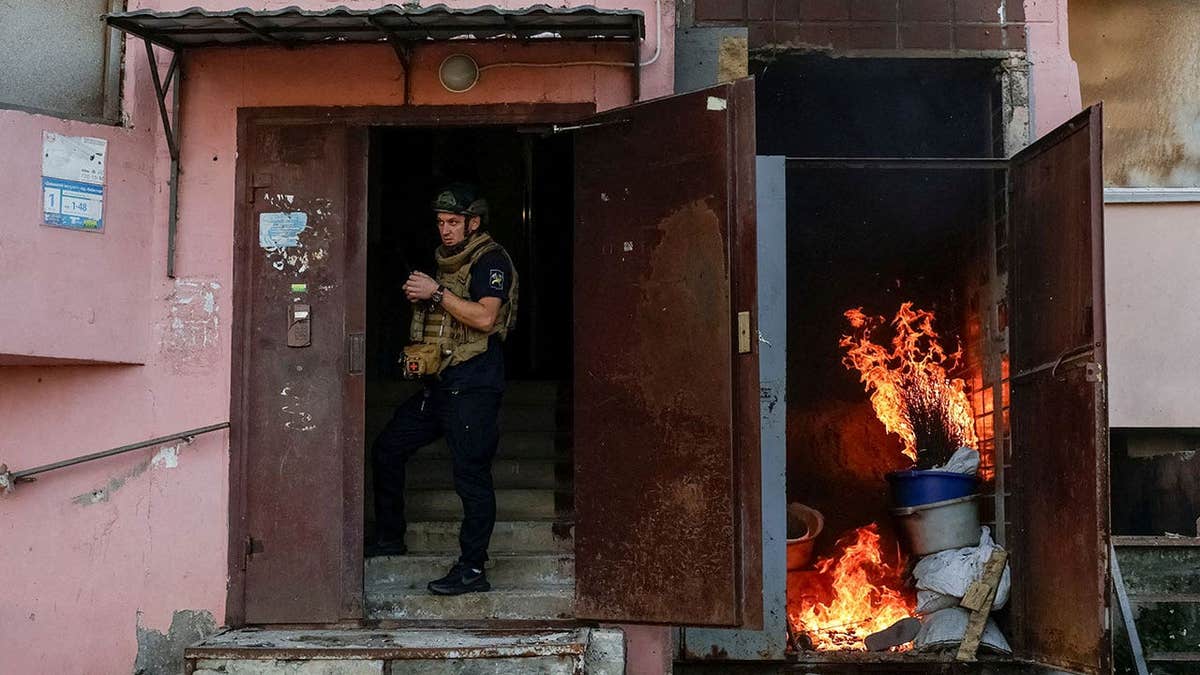 A rescuer takes shelter in an entrance of an apartment building amid the threat of another Russian drone strike