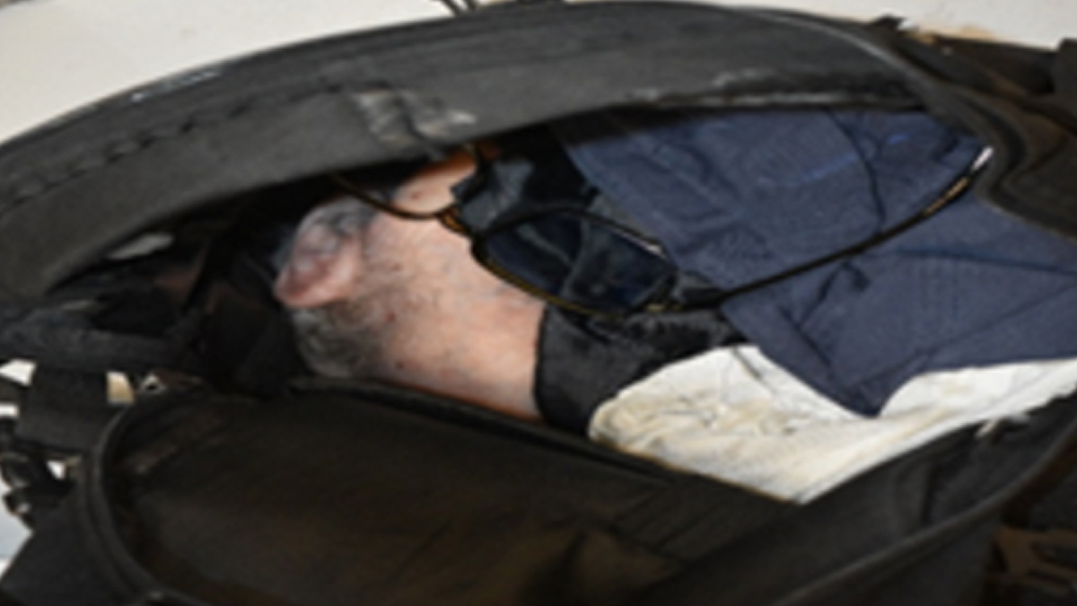 An open black backpack contains a prosthetic mask, glasses and clothing