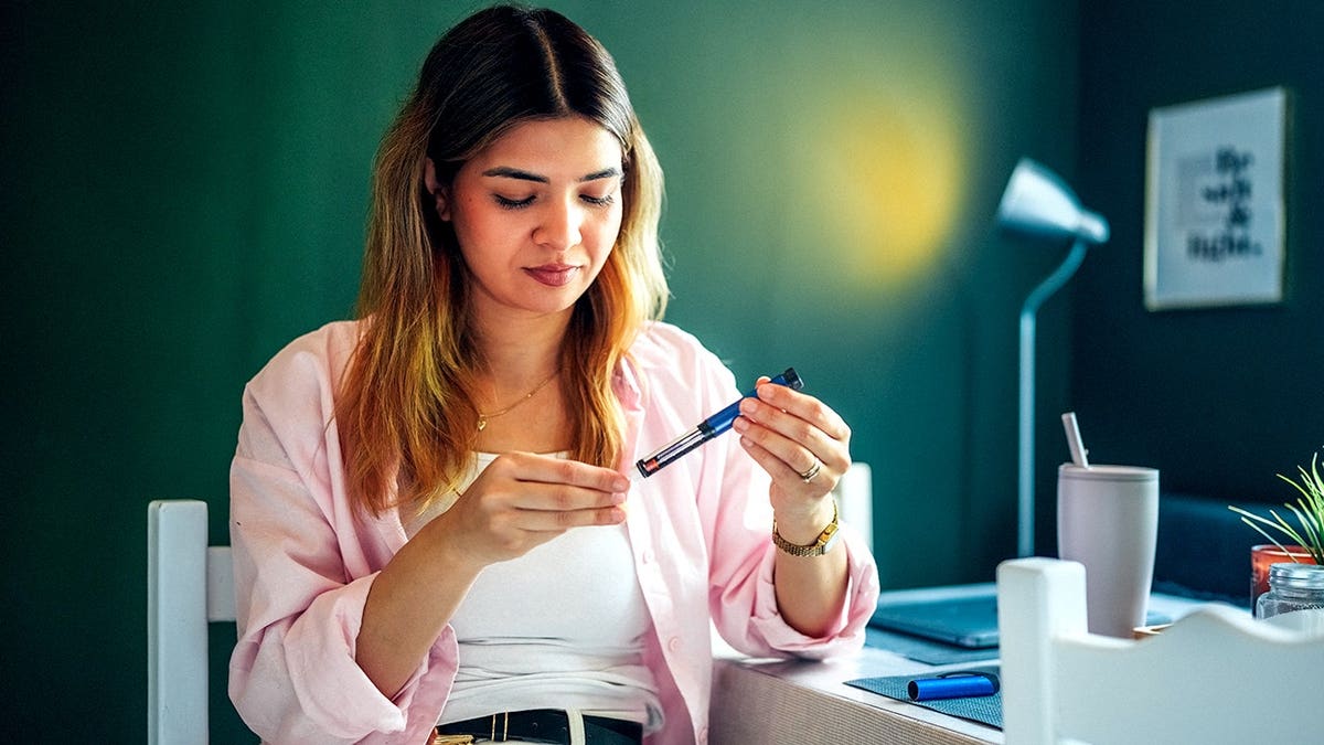 Young woman injects GLP-1 medication into her abdomen while sitting at home.