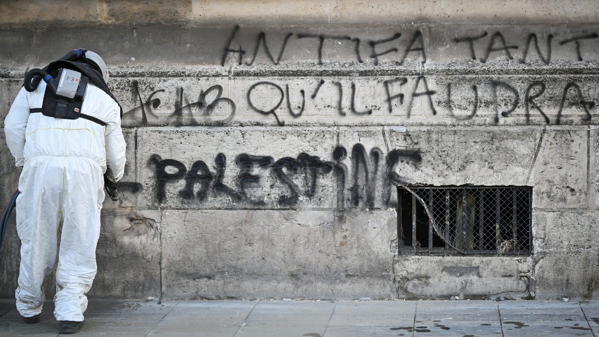 A city employee cleans tags from walls in central Paris, on October 18, 2026 a day after nationwide protests against the "high cost of living".