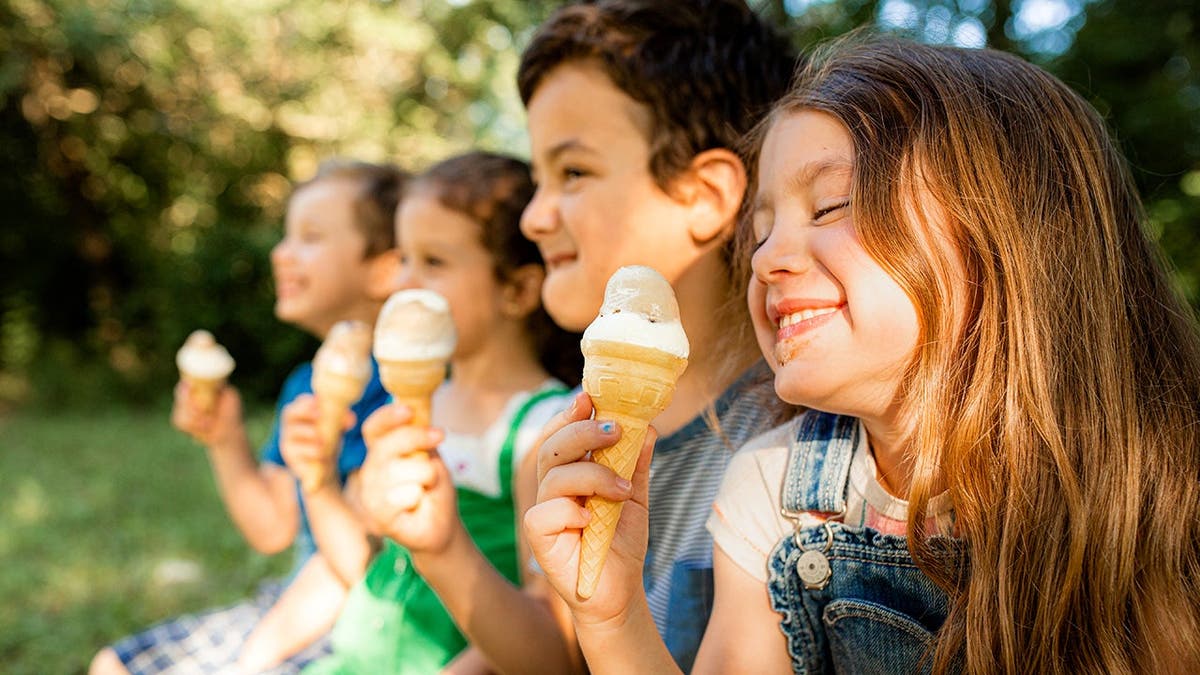 Four children smile and enjoy ice cream cones.