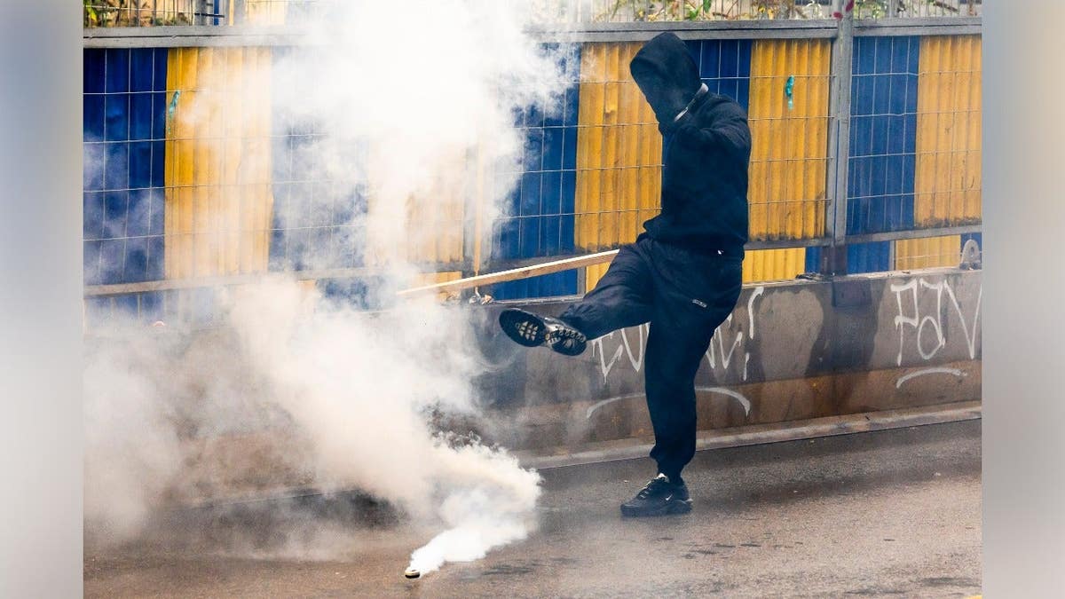 A man kicks a tear gas canister back toward police in Brussels