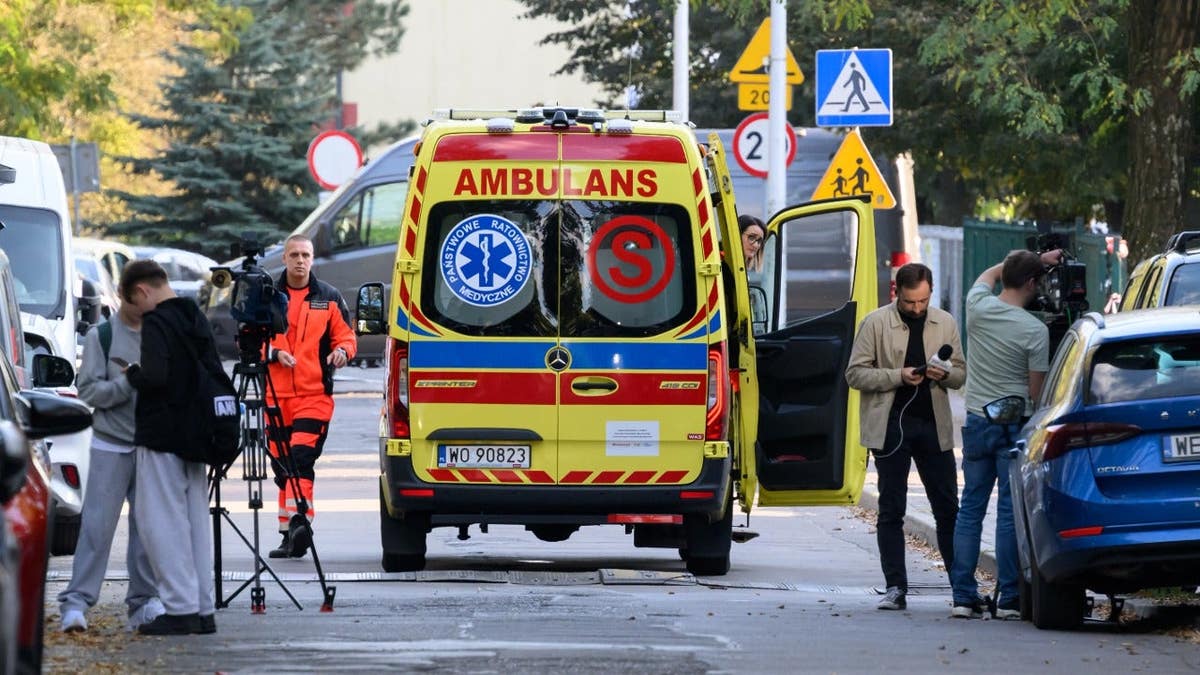 Members of the media work next to an ambulance parked at the scene of a knife attack at a vocational school in Ostroleka