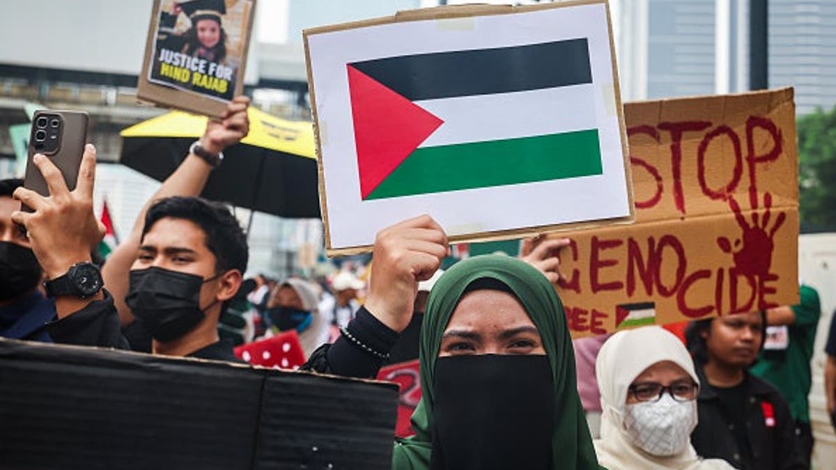 Anti-Israel demonstrators hold a Palestinian flag and signs during a rally in Kuala Lumpur, Malaysia.