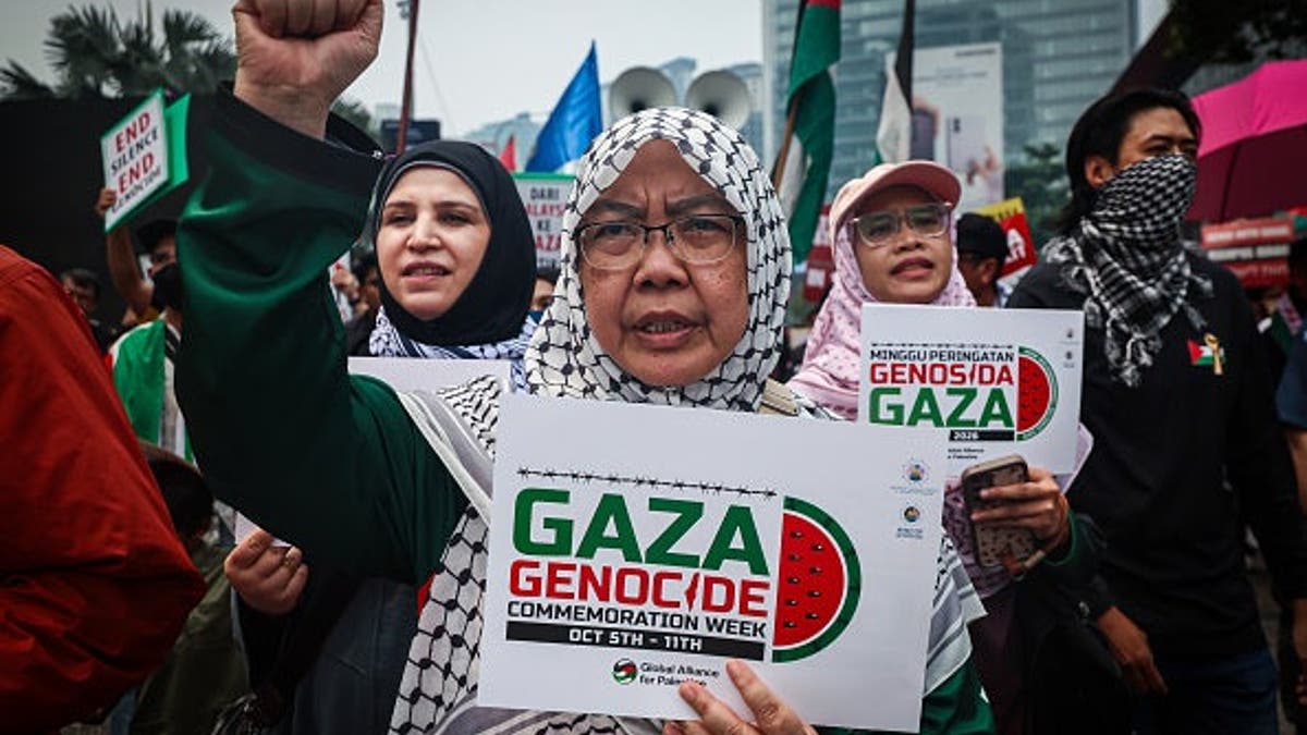 Woman raises her fist holding a placard reading Gaza Genocide at an anti-Israel protest.